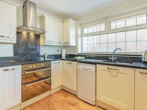 a kitchen with white cabinets and a sink at Seagrass in Greatstone