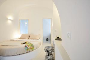 a white room with a bed and a chair at Elegant Santorini House Villa Serenity Caldera Viewoutdoor Hot Tub Private Pool Oia in Thólos +24 photos