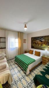 a bedroom with two beds and a painting on the wall at mehek in Asilah