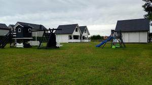 a playground with a slide in a yard with houses at Domek Arkadia in Gąski