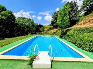 a blue swimming pool with a bench next to it at La Masia del Batlle in Sarroqueta