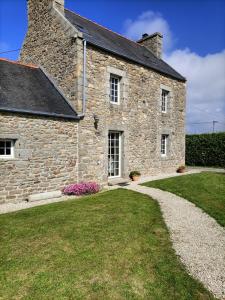 a large stone building with a grass yard next to it at Oudoty in Kerlouan