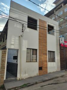 a white building with barred windows on a street at Casinha central Manhuaçu in Manhuaçu