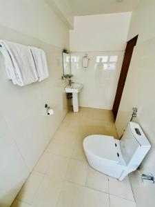 a white bathroom with a toilet and a sink at Kwality Beach Resort in Beni Ghāt