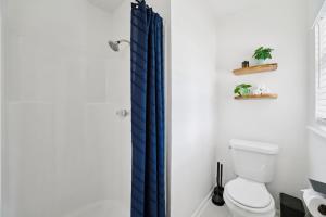 a bathroom with a toilet and a blue shower curtain at Boho Bungalow near DFW Airport in Farmers Branch +25 photos