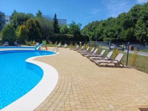 a row of lounge chairs next to a swimming pool at BARBIE & KEN - Apartamenty na ostatnim piętrze w Dominikana Resort & SPA Sianożęty in Sianozety