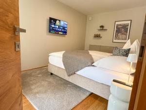una camera da letto con un letto e una TV a parete di Duo - ONE & TWO, Premium Apartments Seekirchen a Seekirchen am Wallersee