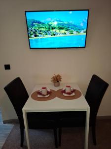un tavolo bianco con due sedie e una TV a parete di Room in SPA " TABARKA " a Spa