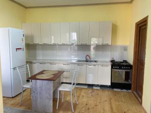 a kitchen with white cabinets and a wooden table at Four Seasons Guest House in Karakol