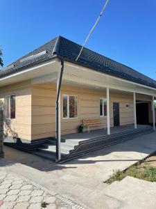 a small house with a bench on the porch at Four Seasons Guest House in Karakol