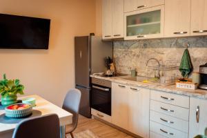 a kitchen with white cabinets and a sink and a table at Къща за гости При Маги и Краси in Belene