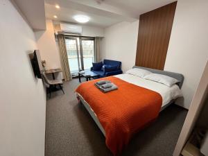 una camera da letto con un letto con una coperta arancione e una sedia di 岛之内Leopard心斎橋602 步行5分钟心斋桥商业区 ad Osaka