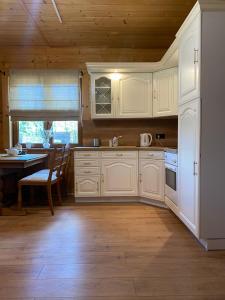 a kitchen with white cabinets and a table and a dining room at CISÓWKA in Sadowie +18 photos