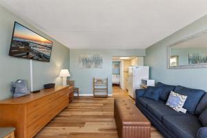 Una sala de estar con un sofá azul y una cocina. en 6201 Ocean Ave, Unit 406 - The Nassau Inn, en Wildwood