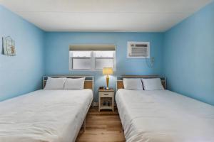 Dos camas en una habitación con paredes azules. en 6201 Ocean Ave, Unit 406 - The Nassau Inn, en Wildwood 22 fotos más