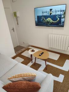 a living room with a flat screen tv on the wall at CMG Studio 3 Petit Bois Place Ducale in Charleville-Mézières