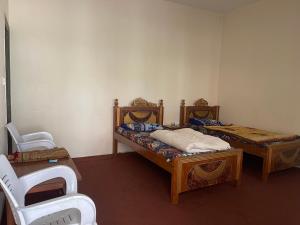 a room with two beds and two chairs in it at Budget Rooms with Garden by Galiyat Inn Balakot in Bālākot