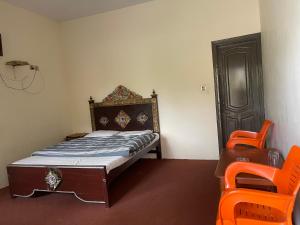 a small bedroom with a bed and an orange chair at Budget Rooms with Garden by Galiyat Inn Balakot in Bālākot