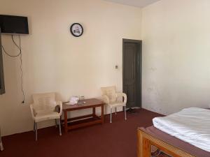 a room with a table and chairs and a clock on the wall at Budget Rooms with Garden by Galiyat Inn Balakot in Bālākot