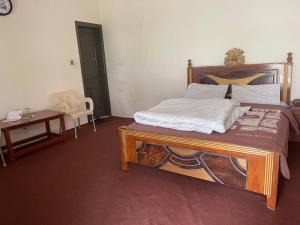 a bedroom with a bed with a wooden frame and a table at Budget Rooms with Garden by Galiyat Inn Balakot in Bālākot
