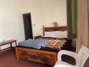 a bedroom with a bed and a chair in it at Budget Rooms with Garden by Galiyat Inn Balakot in Bālākot