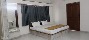a small bed in a room with a window at Tulsi Bliss The Holiday Home in Nashik
