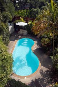 a swimming pool with an umbrella in a yard at Passion Nai Harn Guesthouse in Nai Harn Beach