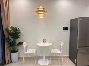 a table and chairs with a table and a refrigerator at Vinhome Grand Park Homestay-HappyStay in Gò Công
