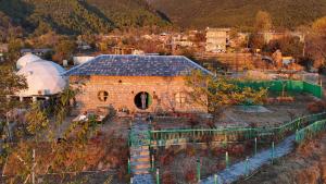 an old brick house with a roof on a hill at Hobbit House Bir in Bīr
