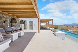 an outdoor patio with white furniture and a swimming pool at Asana Villas by Raise in Márpissa