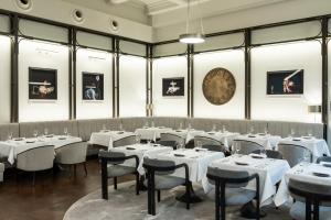 a dining room with white tables and chairs and a clock at The Marmorosch Bucharest, Autograph Collection in Bucharest