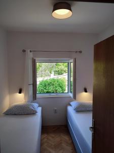 two beds in a room with a window at Apartment Jagoda in Postira
