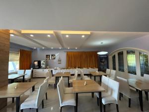 a dining room with wooden tables and white chairs at Diamond Beach Residence Hotel in Draç