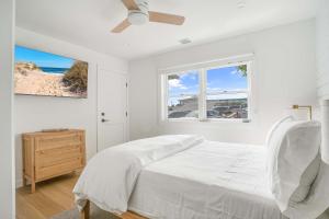 a white bedroom with a bed and a window at Dockside 2BR - Prime Location on the Marina Unit B in Montauk