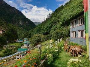 a house with a table and flowers in front of a mountain at Buddha Lodge and Restaurant, Monjo in Khumjung