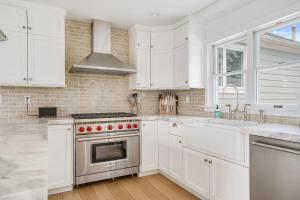 a kitchen with white cabinets and a stove and sink at Dockside 2BR - Prime Location on the Marina Unit B in Montauk