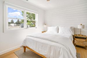 a white bedroom with a bed and a window at Dockside 2BR - Prime Location on the Marina Unit B in Montauk +21 photos