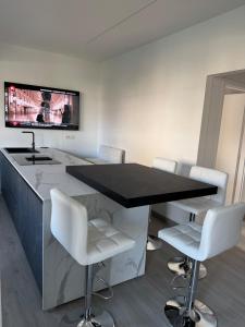 una cucina con bancone nero e sedie bianche di Suite Stella Luxe Mazzini park a Lido di Jesolo Altre 42 foto