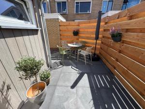 a patio with a table and chairs and a fence at Nieuw in 2025 Bundi Coast Vakantiehuis bij Strand & Duinen in Egmond aan Zee