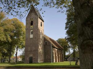 an old brick church with a tower on the grass at 't Westeind, Modern en sfeervol appartement in Norg in Norg