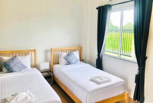 two beds in a room with a window at Farm View Resort @Uthai Thani ฟาร์มวิว รีสอร์ท อุทัยธานี in Nong Khayang