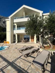 a house with two lounge chairs and a swimming pool at Villa in a quiet area - Private Pool - Sport - Starlink - BBQ in Baška Voda