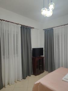 a bedroom with gray and white curtains and a tv at Vila Ester in Ksamil