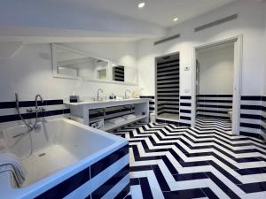 a bathroom with a tub and a black and white tile floor at Grand Hotel Aminta in Sorrento