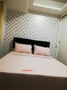 a bedroom with a bed with two pink pillows at Grand Riviera Condotel Near St lukes Medical Center in Manila