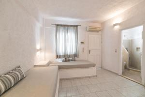 una stanza bianca con un letto e una finestra di Artemis Suites a Megalochori Altre 31 foto