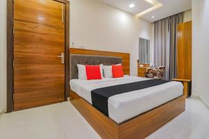 a bedroom with a large bed with red pillows at Capital O Western Galaxy in Amritsar