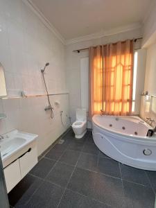 La salle de bains est pourvue d'une baignoire, de toilettes et d'une baignoire. dans l'établissement Al Hussam Hotel Apartments, à Mascate