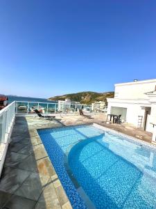 a swimming pool with a view of the ocean at Prainha - Apartamento 3 Quartos in Arraial do Cabo