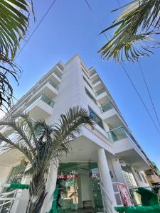 a white building with a palm tree in front of it at Prainha - Apartamento 3 Quartos in Arraial do Cabo +41 photos